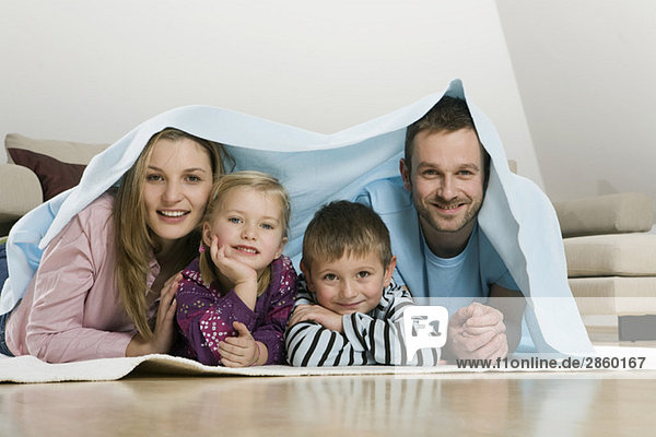 Familie mit Decke bedeckt  lächelnd