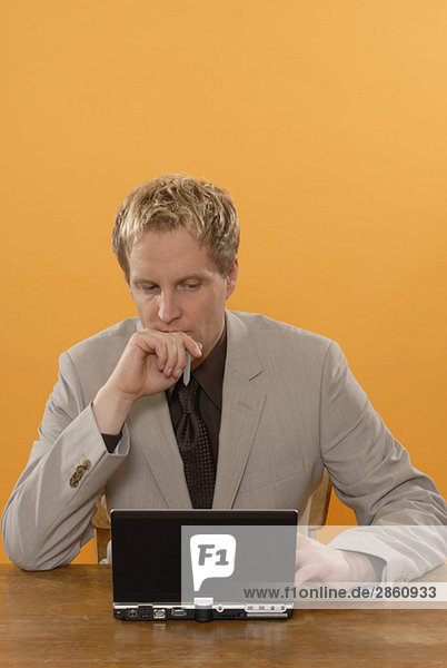 Businessman sitting at laptop  musing  portrait