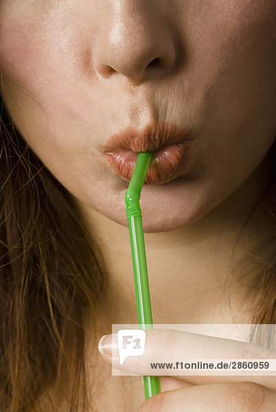 Young woman drinking through straw  close up