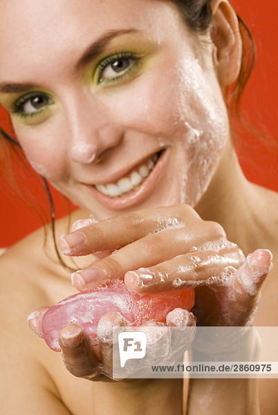 Young woman holding cake of soap  smiling  close up