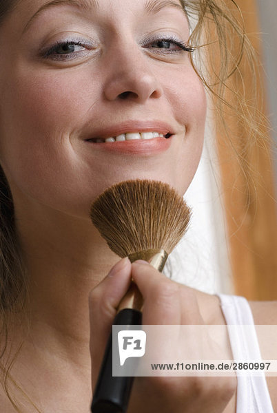 Young woman using make-up brush  close up