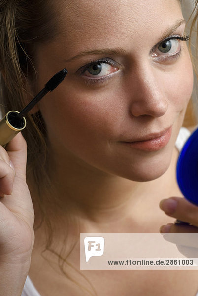 Young woman applying mascara  close-up  portrait
