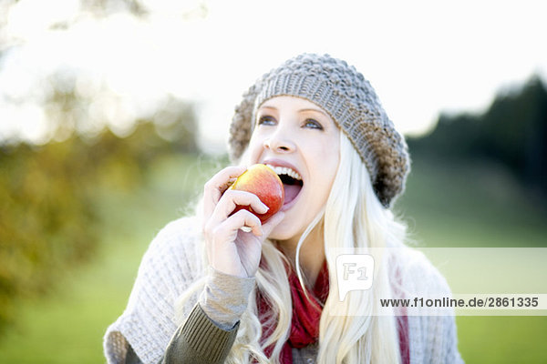Junge Frau beißt in einen Apfel  Portrait
