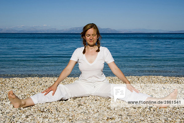 Greece  Ithaca  Woman exercising yoga on beach