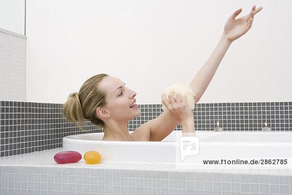 Young woman taking bath  washing arm  side view