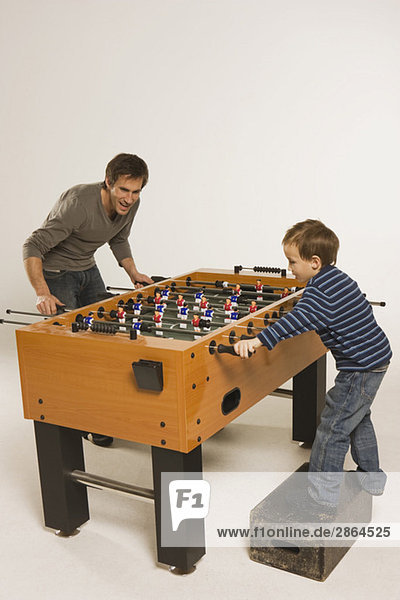 Vater und Sohn (4-5) spielen Tischfußball
