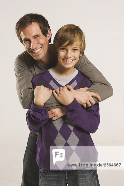 Vater umarmt Sohn (14-15)  lächelnd  Portrait
