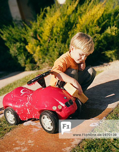 Ein Junge eine rote Auto waschen.