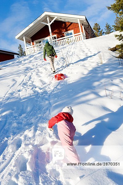 Mutter und Tochter im Schnee spielen.