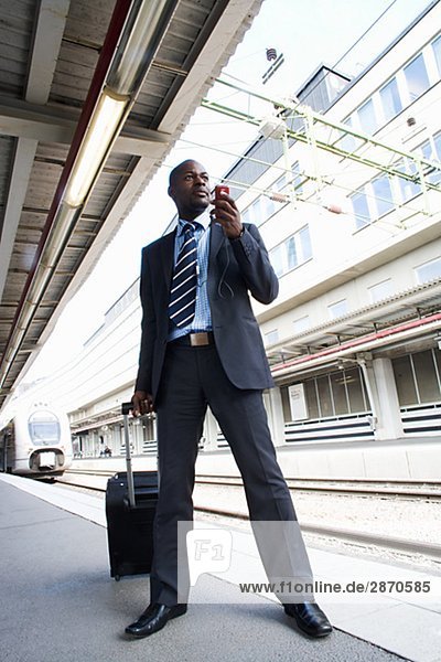 Ein Geschäftsmann mit einer Tasche mit einem Mobiltelefon am Bahnhof Stockholm Schweden.