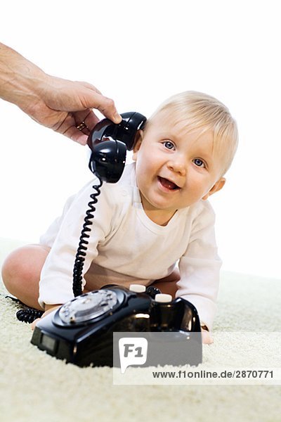 Baby playing with a telephone.