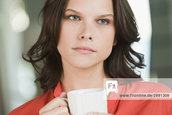 Frau hält eine Tasse Tee und denkt nach