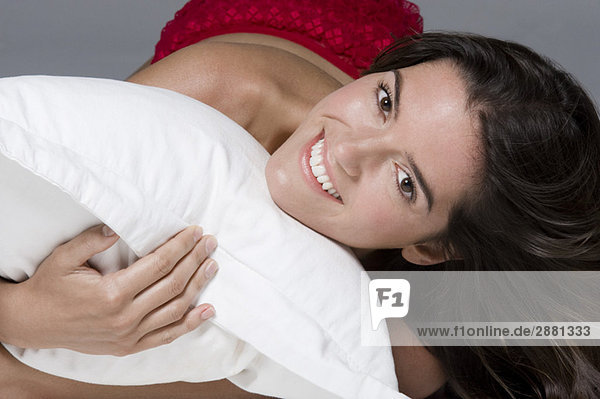 Porträt einer Frau  die ein Kissen umarmt und lächelt