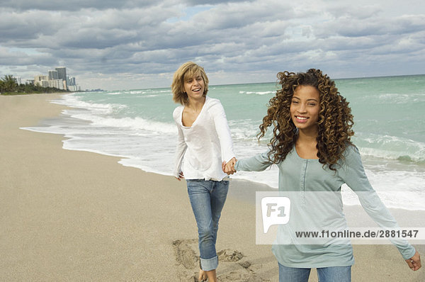 Mädchen mit der Hand eines Teenagers am Strand