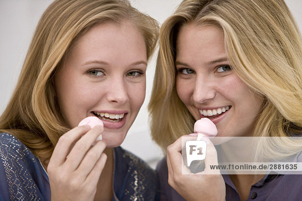 Two women eating mushroom shaped candies