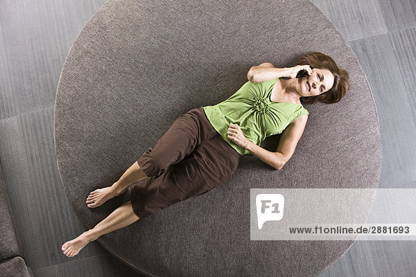 Woman lying on a round sofa and talking on a mobile phone