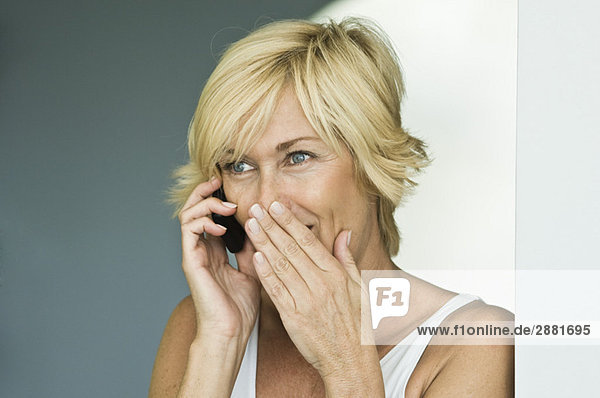 Frau spricht auf dem Handy und ist überrascht.