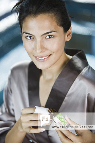 Frau hält eine Flasche Aromatherapieöl und lächelt