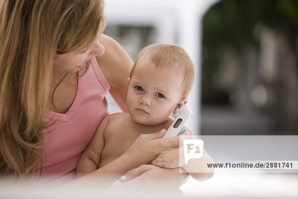 Woman taking her daughter's temperature with a thermometer