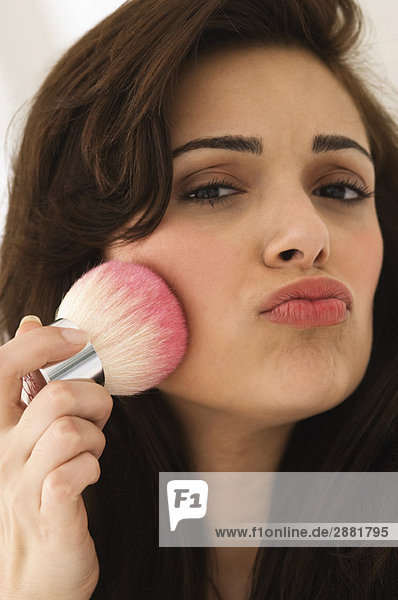 Portrait of a woman applying blusher on her face