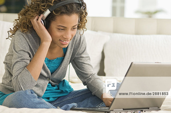 Mädchen arbeitet an einem Laptop und hört sich Kopfhörer an