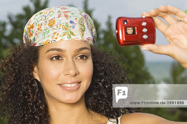 Frau macht ein Foto von sich selbst mit einer Digitalkamera
