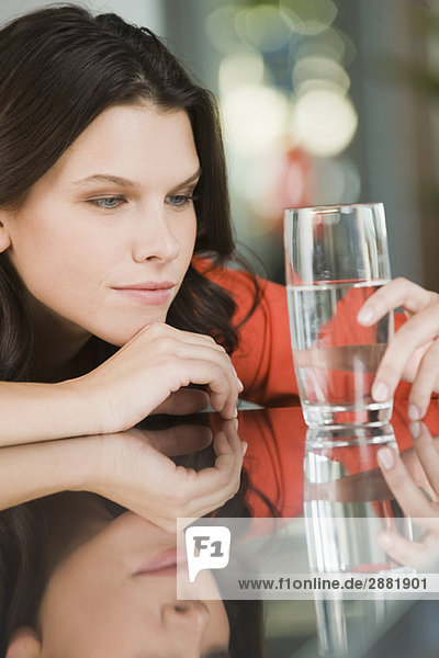 Frau schaut auf ein Glas Wasser.