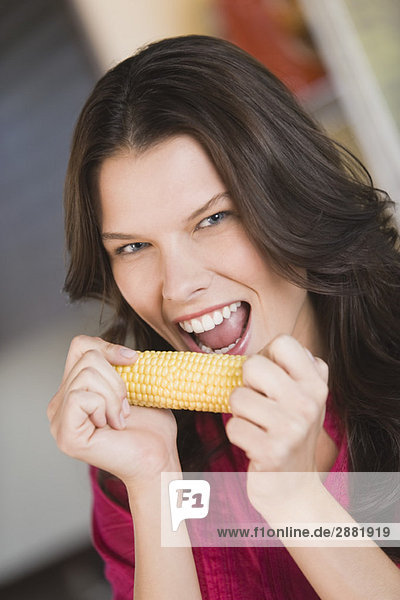 Frau isst Mais auf dem Kolben