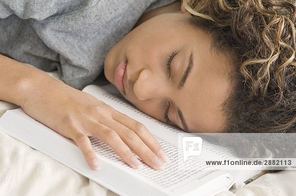 Mädchen schläft mit dem Gesicht nach unten auf einem Buch