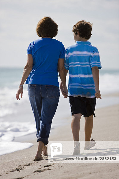 Frau mit ihrem Enkel beim Spaziergang am Strand