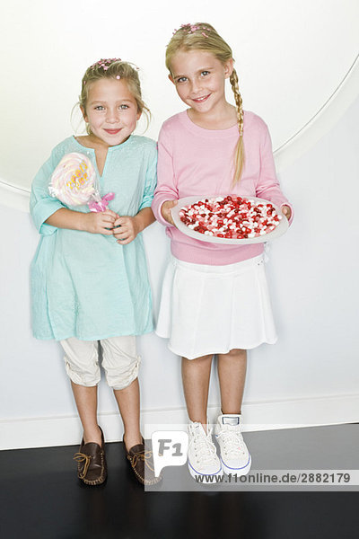 Mädchen hält einen Teller mit Geleebohnen und ihre Freundin steht neben ihr.