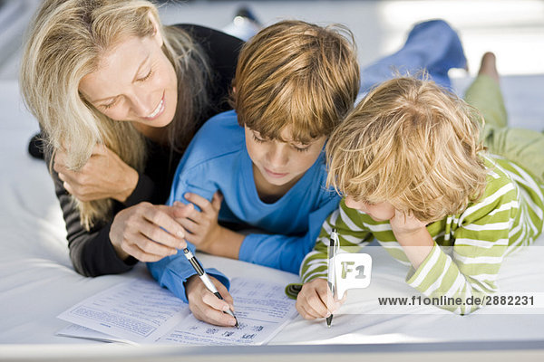 Frau hilft ihren Söhnen bei den Hausaufgaben