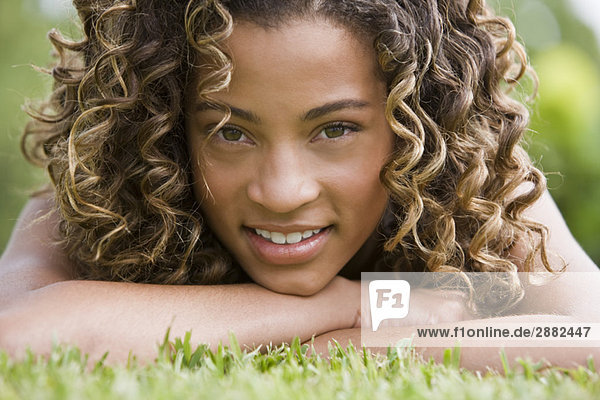 Porträt eines Mädchens auf Gras liegend und lächelnd