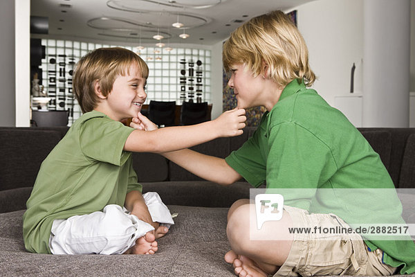 Zwei Jungen  die sich am Kinn berühren und lächeln.