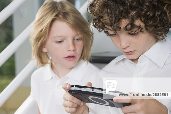 Boy playing a video game and his sister looking at it