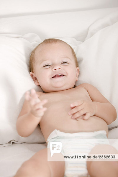 Close-up of a baby girl lying on the bed and smiling