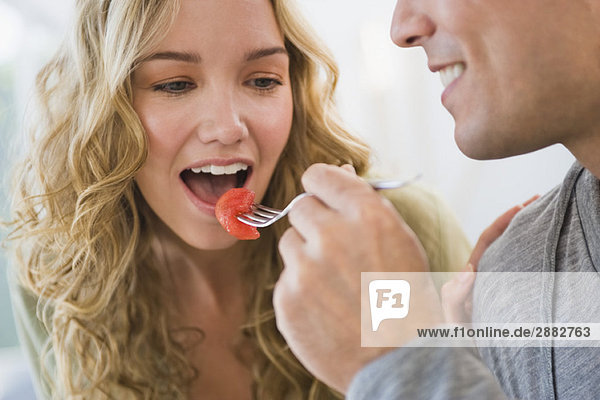Mann füttert seine Frau mit Erdbeeren
