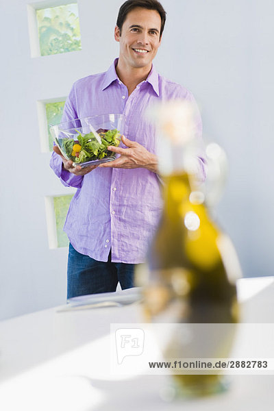 Mann hält eine Schüssel Salat und lächelt