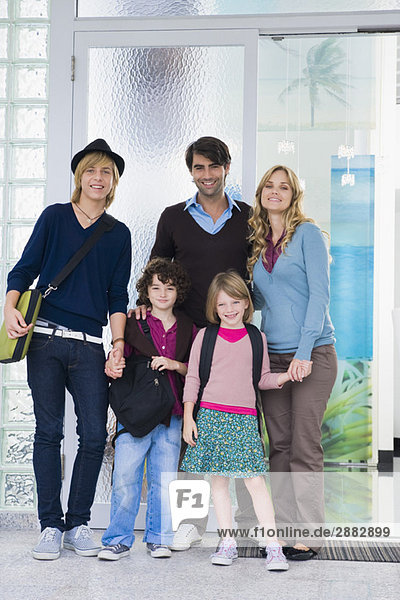Ein Paar steht mit seinen Kindern und einem Kindermädchen vor der Haustür.