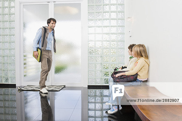 Man walking towards his children waiting in an entrance hall