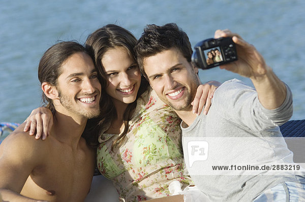 Drei Freunde  die mit einer Digitalkamera ein Foto von sich machen