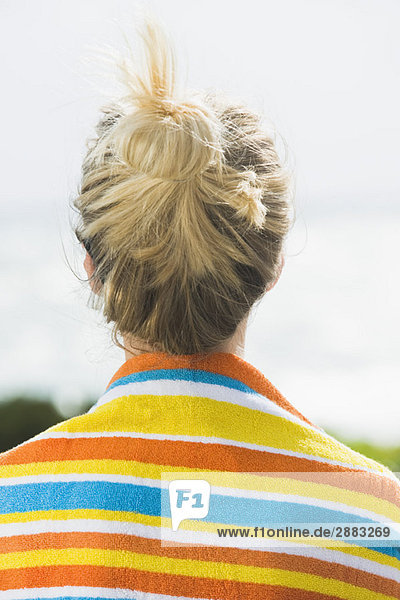 Rückansicht einer Frau mit einem Strandhandtuch um die Schultern