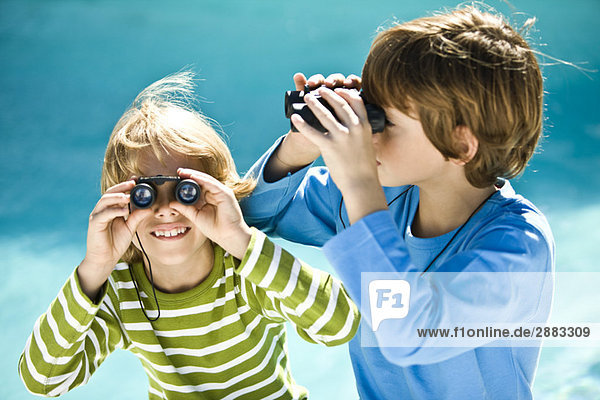 Two boys looking through binoculars