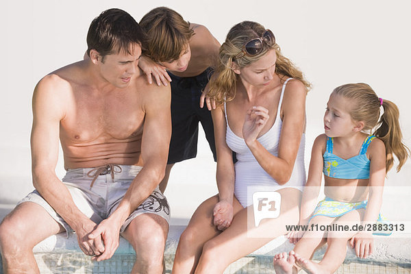 Familie am Pool sitzend