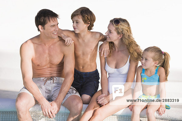 Familie am Pool sitzend und lächelnd