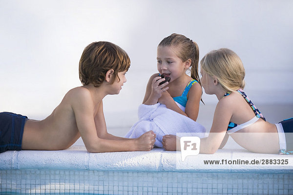 Zwei Mädchen und ein Junge am Pool