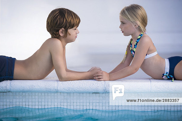 Junge mit einem Mädchen  das am Pool liegt.