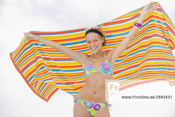 Porträt einer Frau  die ein Strandtuch hält und lächelt