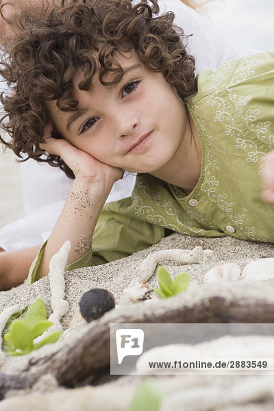Porträt eines am Strand liegenden Jungen