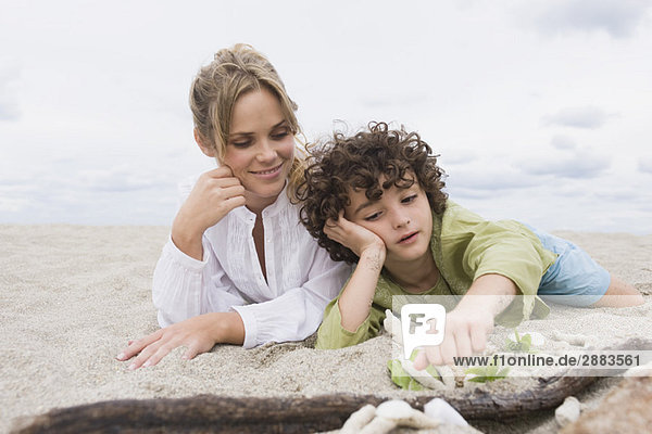 Boy lying with his mother on the beach
